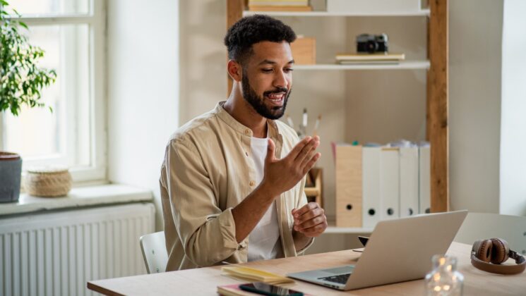 A man looking at a computer screen and using sign language