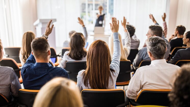 An audience seen from behind with their hands in the air