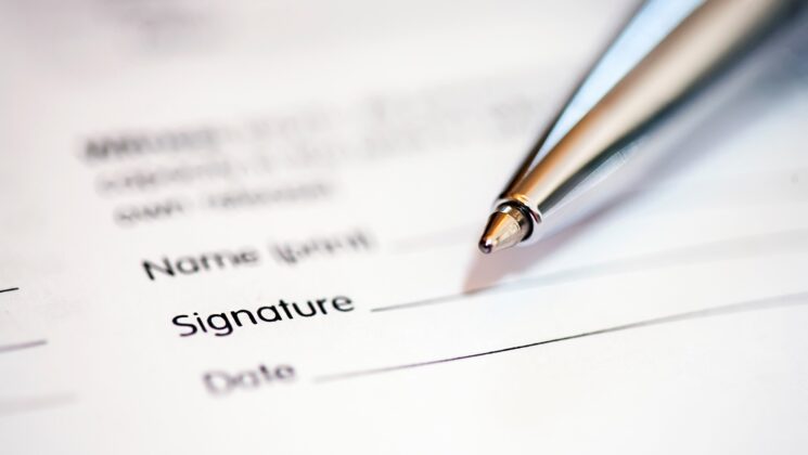 A pen and form requesting name, signature and date