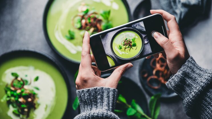 A mobile phone being used to take a photograph of some green soup